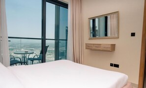Ein Hotelzimmer mit großem Fenster, einem Bett, einem kleinen Tisch mit Stühlen und einem Spiegel an der Wand.