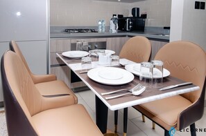 A modern dining area with a rectangular table set for four, equipped with plates, cutlery, and glasses.