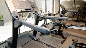 A gym with treadmills, weight machines, and a large window. - Stylish Sanctuary Studio with Pool view (Dubai)