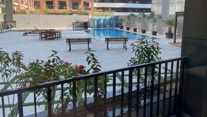 A rooftop pool area with lounge chairs and potted plants, surrounded by modern buildings. - Stylish Sanctuary Studio with Pool view (Dubai)