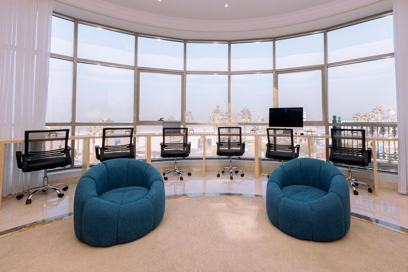 Ein modernes Büro mit großen Fenstern, schwarzen Bürostühlen und blauen Sitzsäcken.