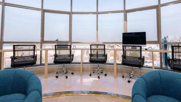 A modern office space with large windows, black office chairs, and a blue sofa.
