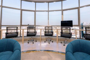 Een moderne kantoorruimte met grote ramen, zwarte bureaustoelen en een blauwe bank.