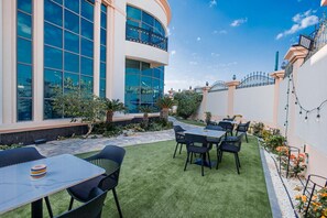 A courtyard with outdoor seating, a building with large windows, and a well-maintained garden.