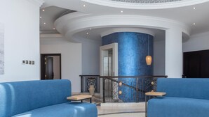 Una hall con una parete decorata in blu, una scala con ringhiere elaborate e due divani blu.