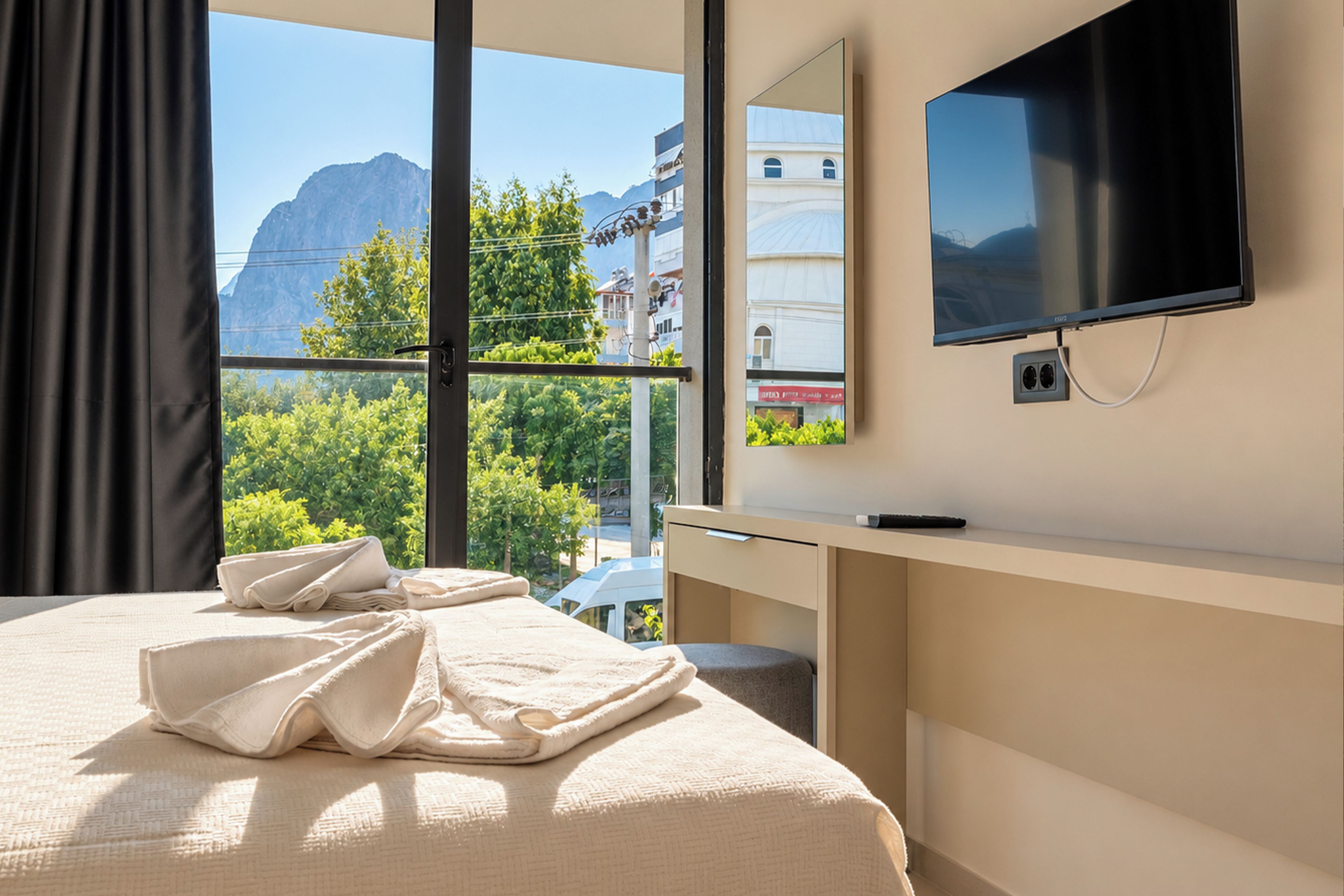 Ein Hotelzimmer mit einem Bett, einem Schreibtisch, einem Flachbildfernseher und einem großen Fenster mit Bergblick.