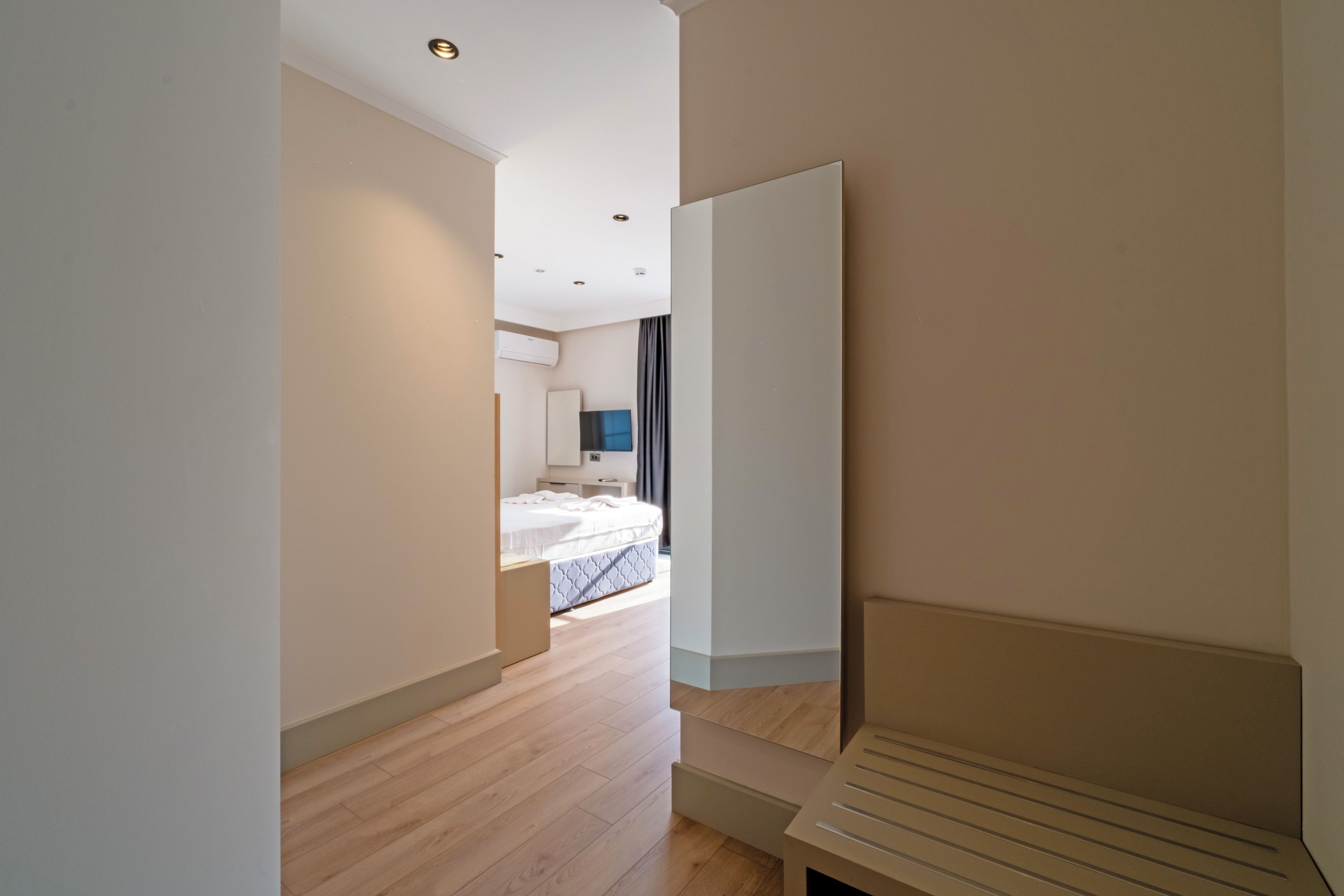 A modern hotel room with a bed, a flat-screen TV, and a large window.