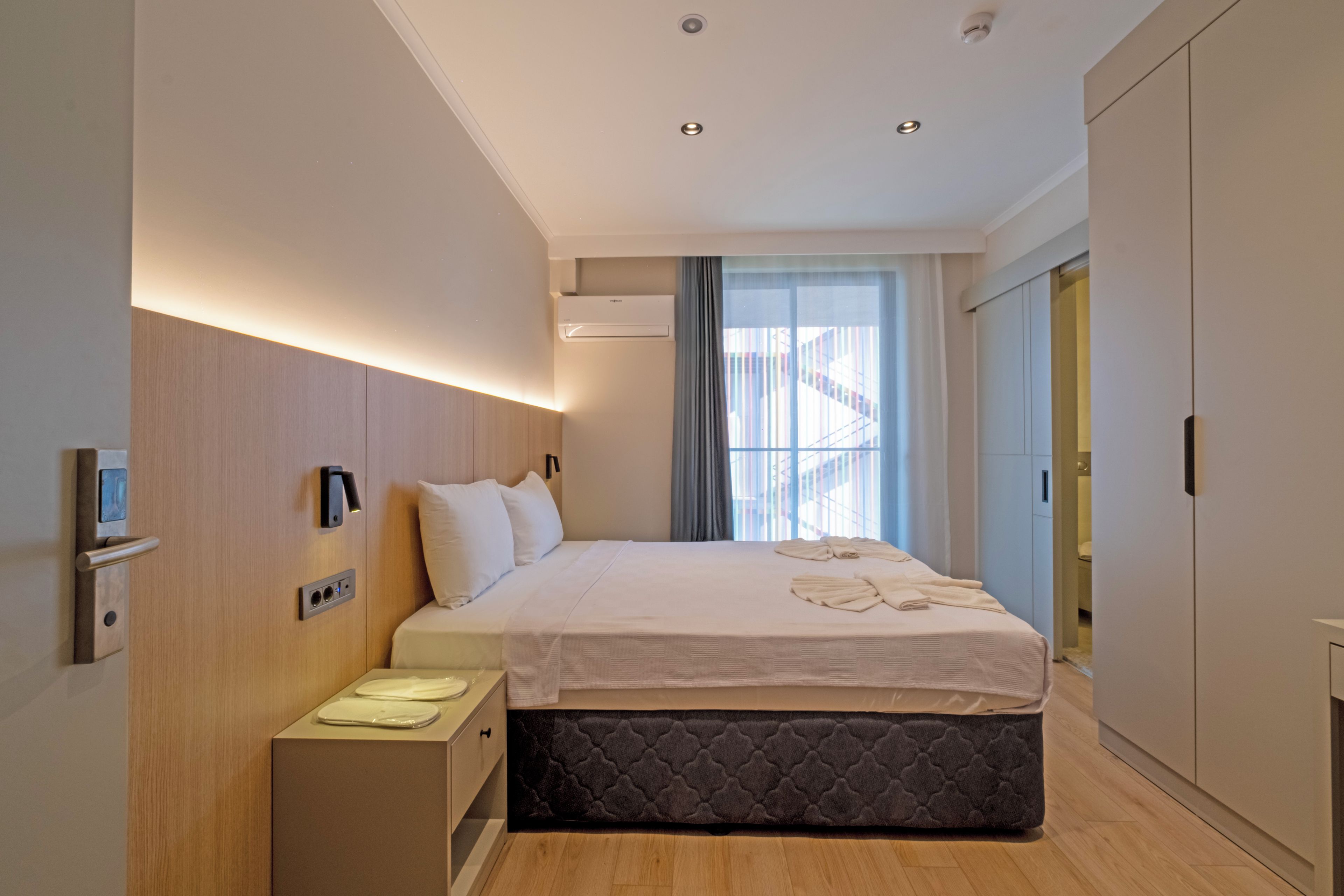 Een moderne hotelkamer met een bed, nachtkastje en een kledingkast.