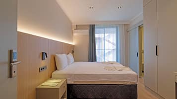 Een moderne hotelkamer met een bed, nachtkastje en een kledingkast.