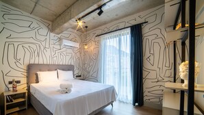 A modern bedroom with a large bed, a bedside table, a wall-mounted air conditioner, and a window with curtains. - Rudblu Suites (Konyaalti)