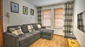 A modern living room with a grey sectional sofa, plaid curtains, and framed sports pictures on the wall.