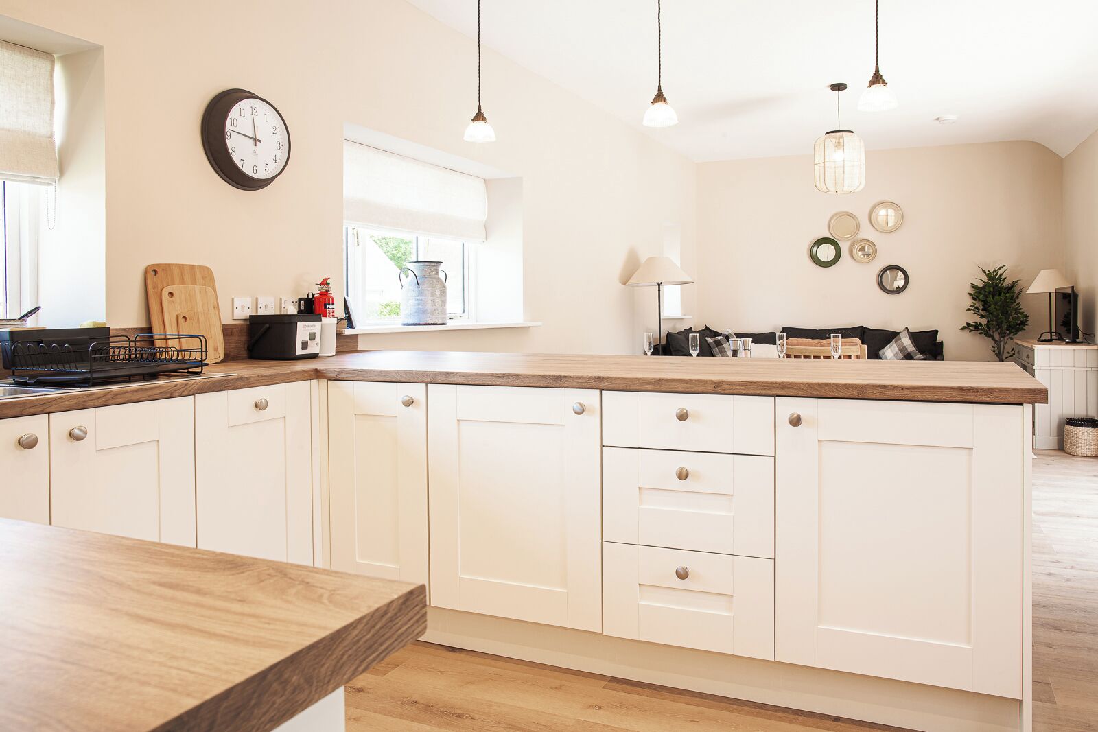 A modern kitchen with white cabinetry, a wooden countertop, and pendant lighting.