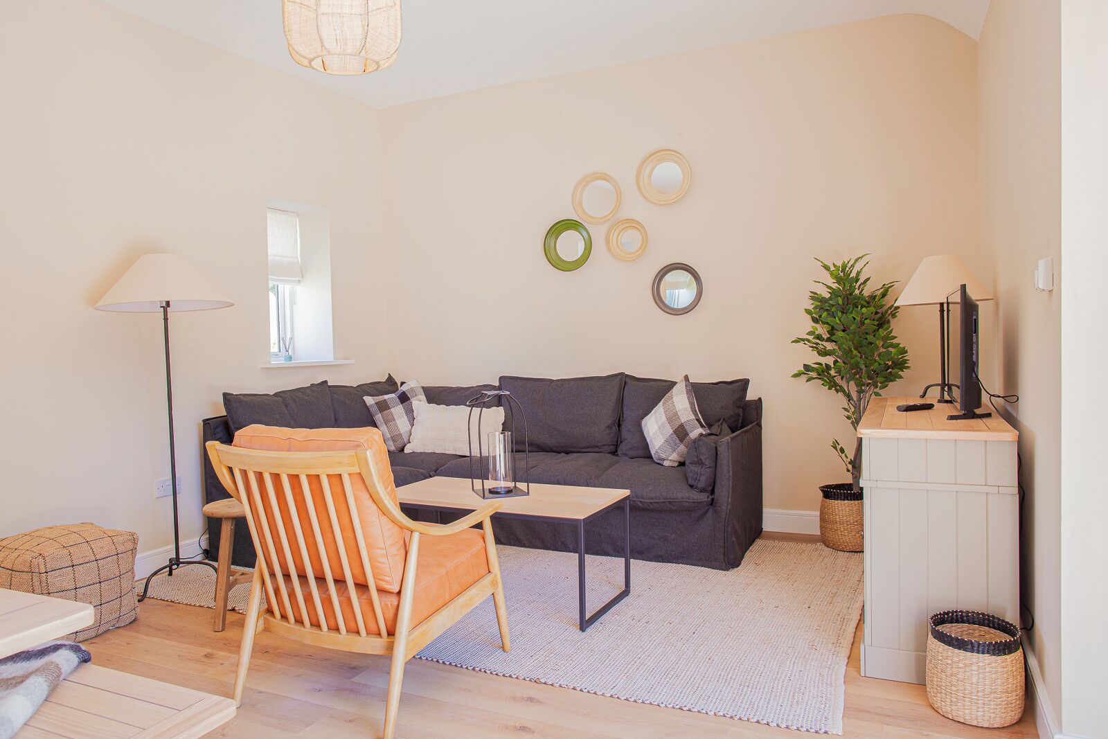 A modern living room with a sofa, a wooden chair, a coffee table, and a TV on a stand.