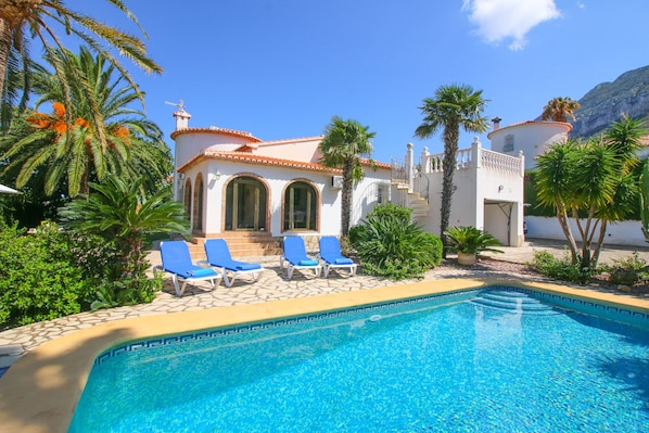 Relax by the serene pool surrounded by lush gardens and palm trees.