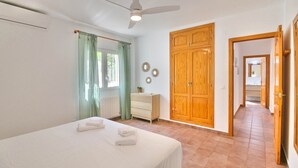 A bedroom with a bed, a dresser, a ceiling fan, and a wooden wardrobe. - All inclusive villa in Denia with pool 4p (Denia)