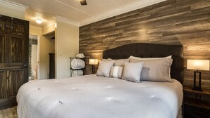A large bed with a tufted headboard, two bedside lamps, and a wooden headboard wall. - Modern Style 2 Bed Condo Pool in Gatlinburg (Gatlinburg)