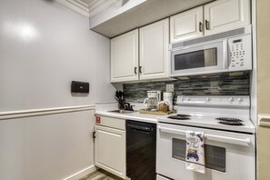 A kitchen with white cabinets, a microwave, a coffee maker, and a dishwasher. - Modern Style 2 Bed Condo Pool in Gatlinburg (Gatlinburg)