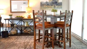 A dining area with a table and four chairs, a lamp, a painting, and a window. - Amazing Lakefront Getaway (Hot Springs)
