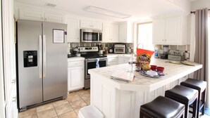 A modern kitchen with white cabinetry, stainless steel appliances, and a central island with bar stools. - Amazing Lakefront Getaway (Hot Springs)
