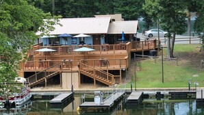 A lakeside building with a deck, outdoor seating, and a dock. - Amazing Lakefront Getaway (Hot Springs)