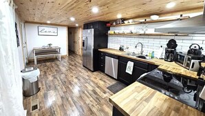 Une cuisine moderne avec un plancher en bois, un réfrigérateur en acier inoxydable, un four à micro-ondes et une machine à café.