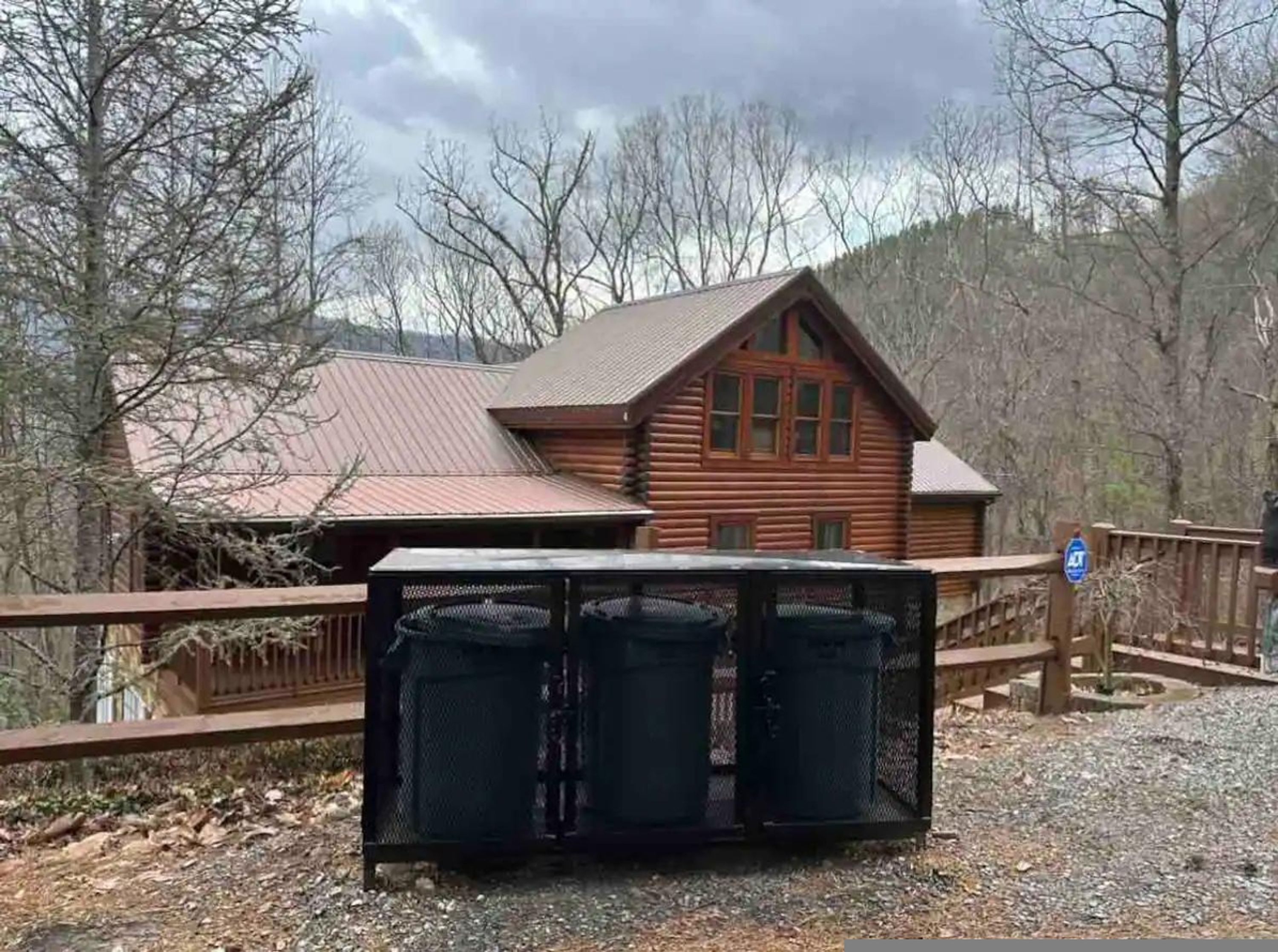 A wooden cabin with a metal fence in front.