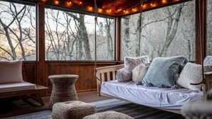 A cozy cabin interior with a wooden floor, a hanging swing bed, and a rustic bench. - High-end Luxury Cabin Sauna Hot Tub Gameroom (Sevierville)