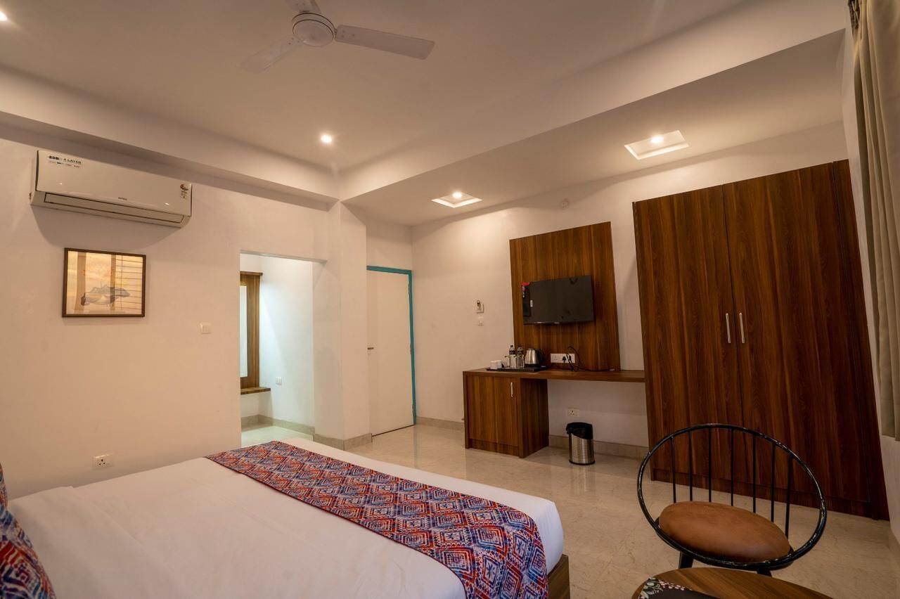 A hotel room with a bed, a desk, a chair, a wardrobe, and a television.