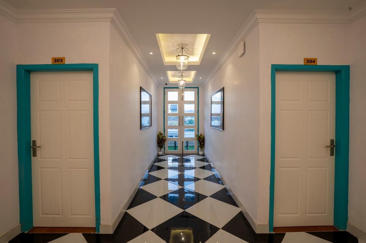 A hotel hallway with black and white checkered flooring, teal-framed doors numbered 303 and 304, and a ceiling light fixture.