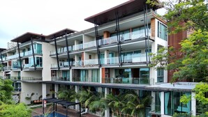 A multi-story hotel with a rooftop pool area, balconies with glass railings, and lush greenery. - Best Sea View 500m 2 Beach Modern C1 (Rawai)