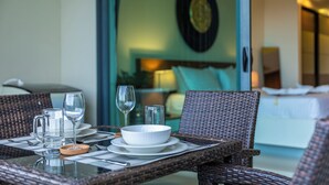 A dining table set with plates, bowls, glasses, and a pitcher, with wicker chairs and a glass table. - Best Sea View 500m 2 Beach Modern C1 (Rawai)