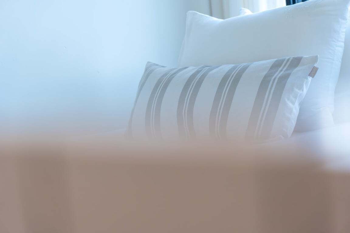 A bed with white pillows and a striped pillow.