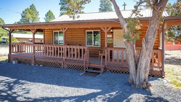 A rustic wooden cabin with a porch, a large tree in front, and a gravel driveway. - The Lone Pine (Heber-Overgaard)