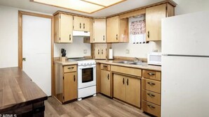 A kitchen with wooden cabinets, a stove, a sink, and a refrigerator. - The Lone Pine (Heber-Overgaard)