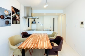 Een moderne keuken met een centraal eiland, een eettafel met stoelen, en een magnetron boven het eiland.