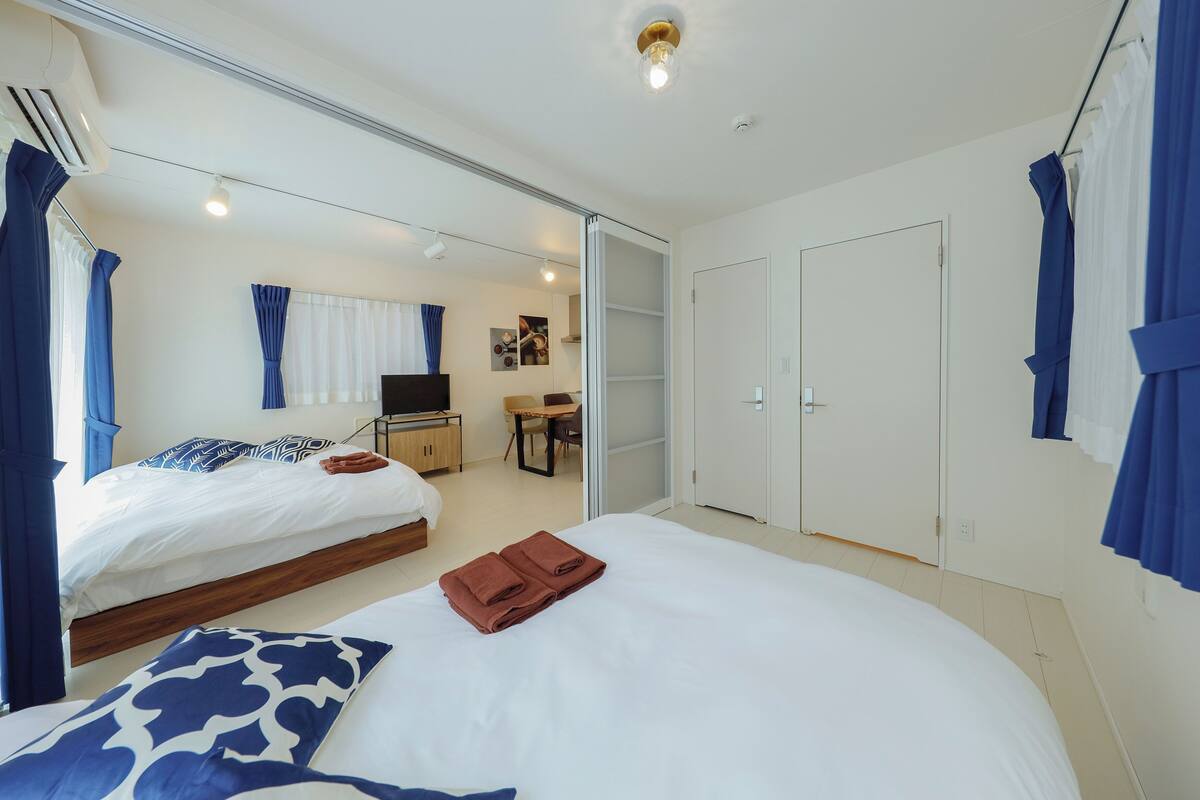 Habitación de hotel con dos camas, un escritorio, una silla y un armario.