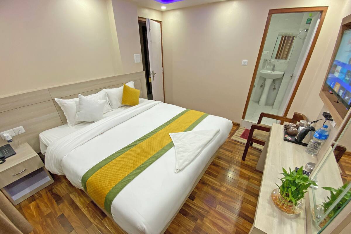 A hotel room with a bed, bedside table, and a desk with a chair.