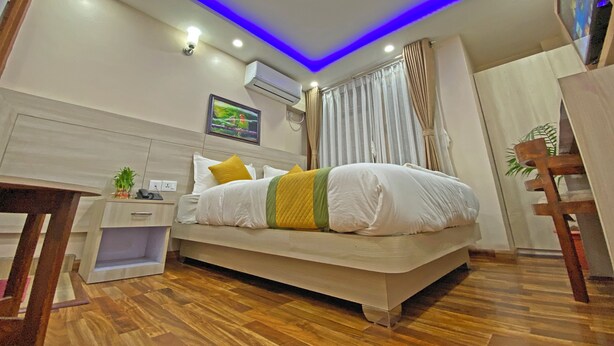 A modern bedroom with a bed, bedside table, and a small desk. - Hotel Aaradhya (Kathmandu)