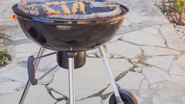 A barbecue grill outdoors with a stone pathway leading to a staircase.