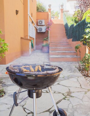 A barbecue grill outdoors with a stone pathway leading to a staircase.