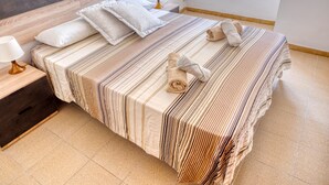 A neatly made bed with striped bedding, a bedside lamp, and a wooden headboard.