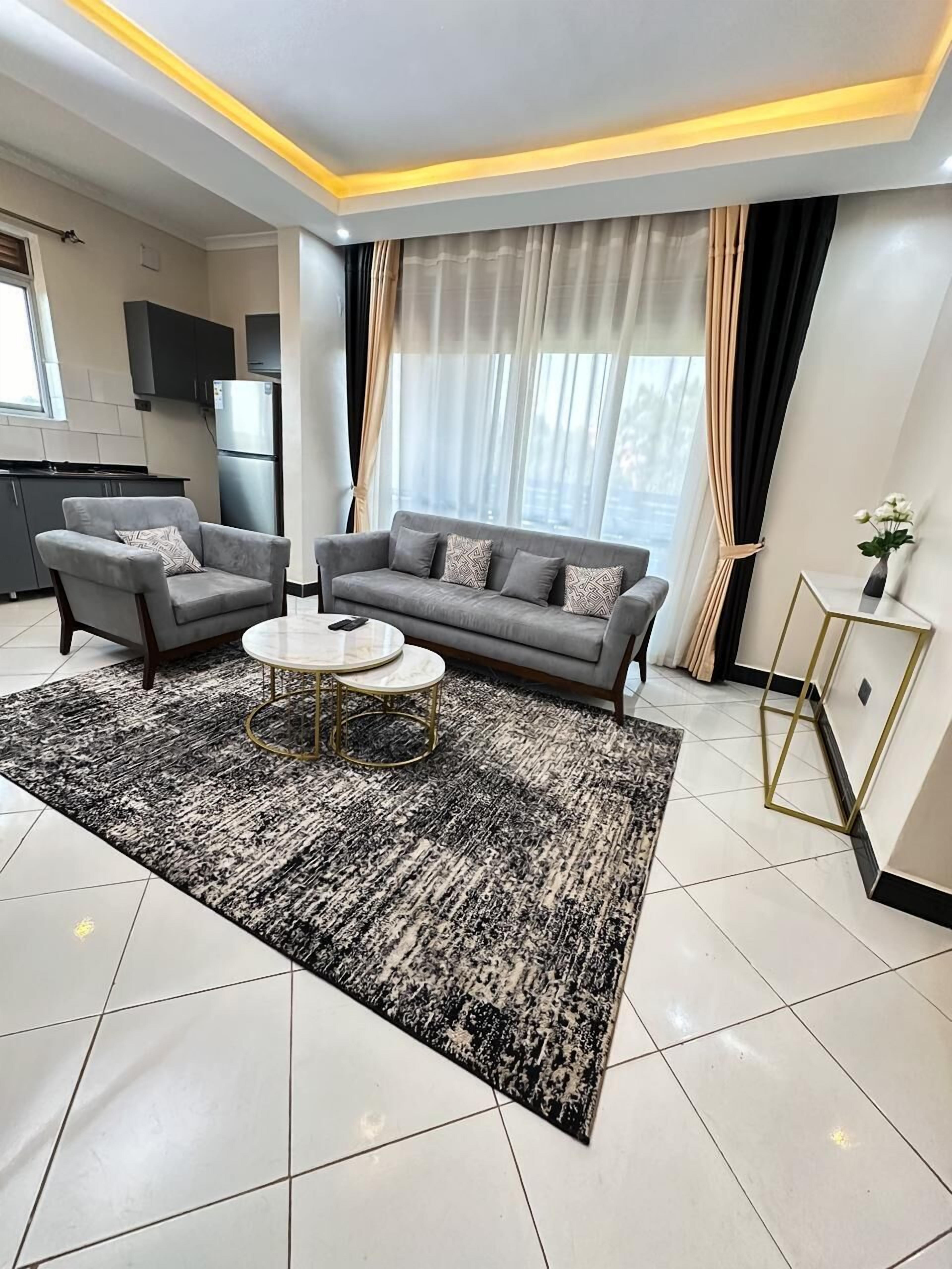 Een moderne woonkamer met een grijze bank, twee fauteuils, een salontafel en een kamerkleed met dessin.