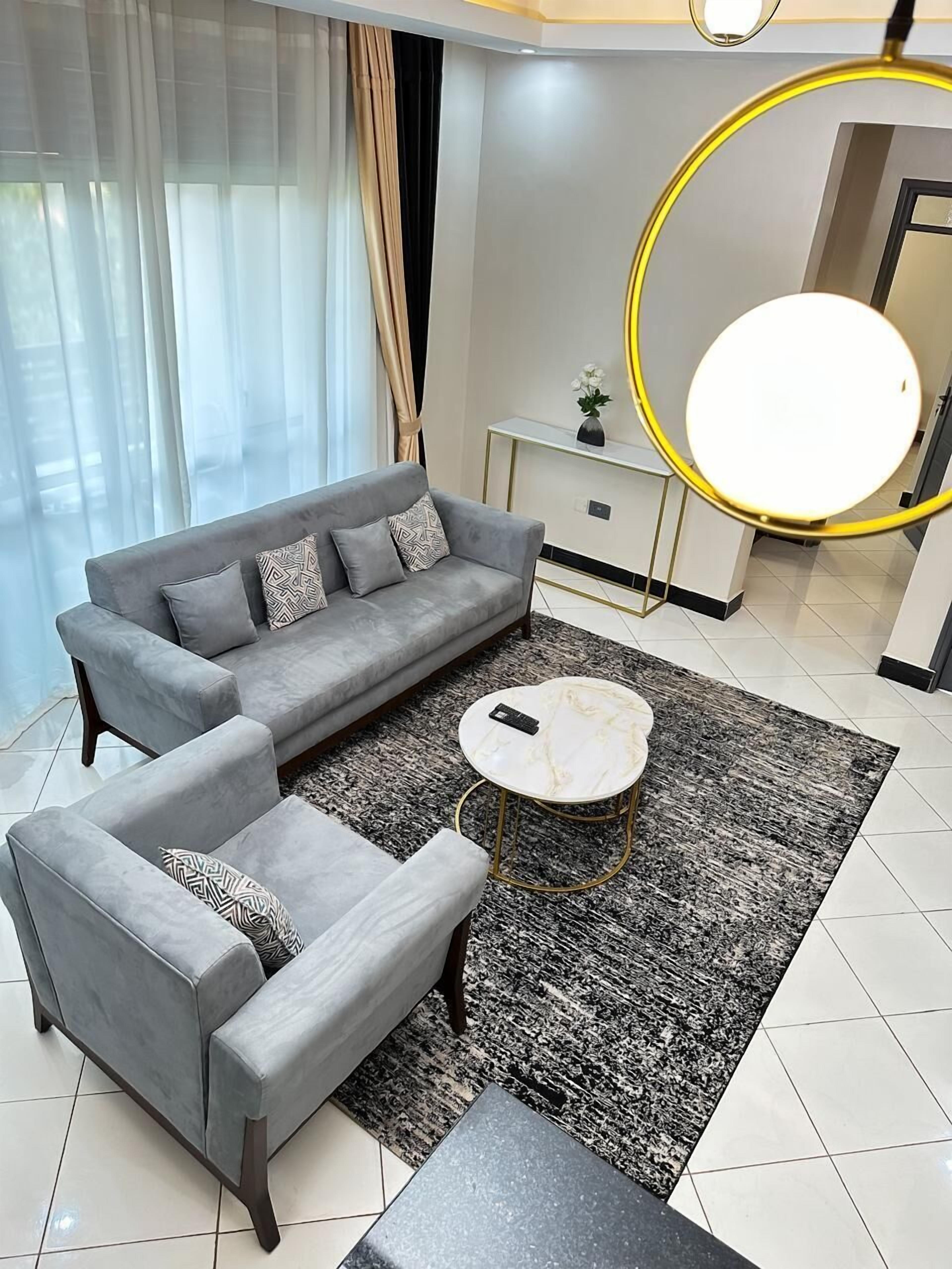 A modern living room with a grey sofa, a matching armchair, a round coffee table, and a small side table with a vase.