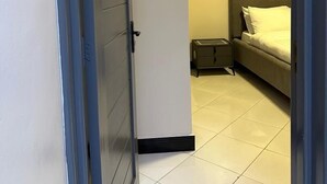 Ein schmaler Flur, der zu einem Schlafzimmer mit Bett und Nachttisch führt.