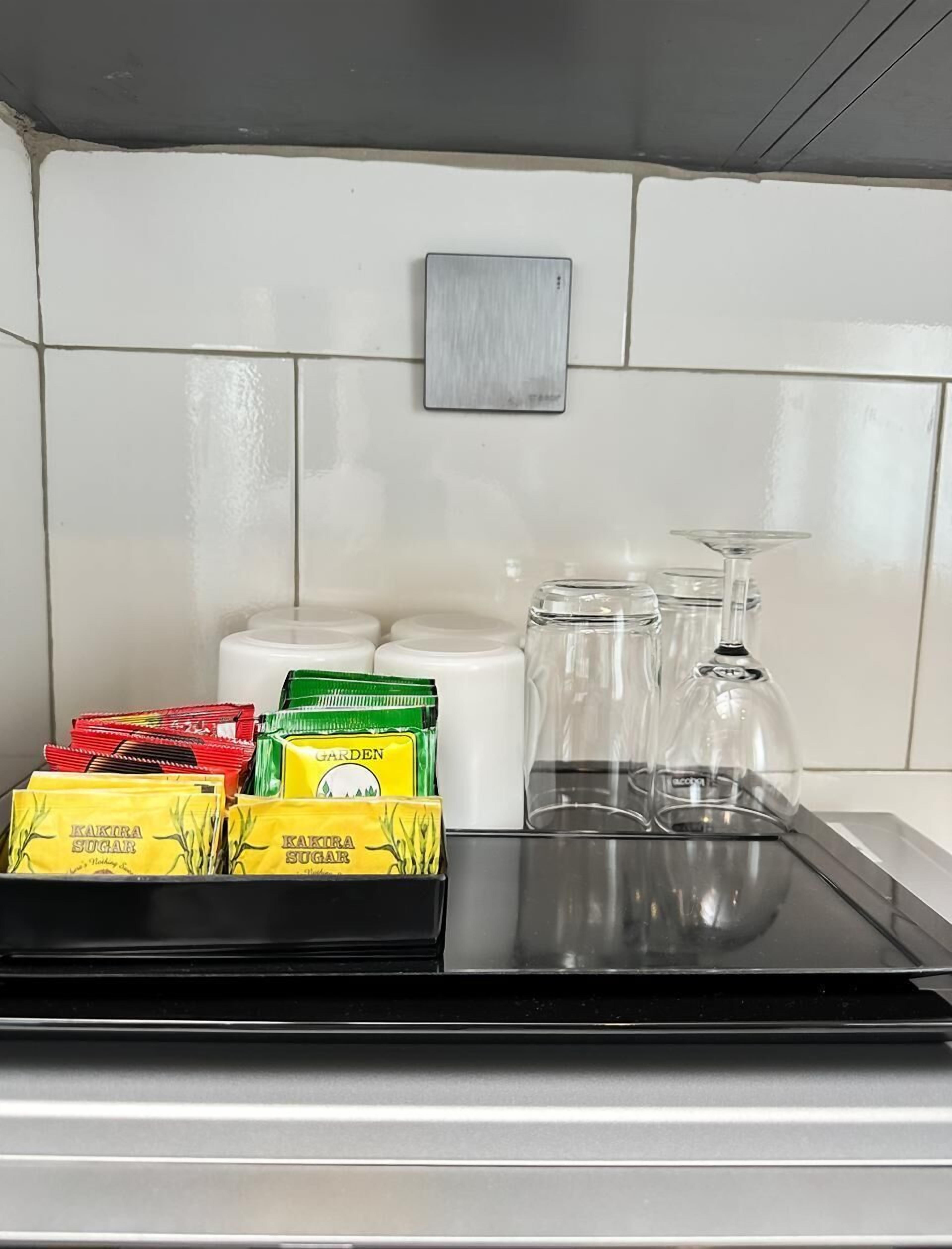 A kitchen counter with a black tray holding sugar packets and a glass jar.