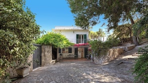 A stone-paved courtyard with a white building featuring a balcony and green shutters. - 4076 Villa Baia D'oro by Barbarhouse (Pulsano)