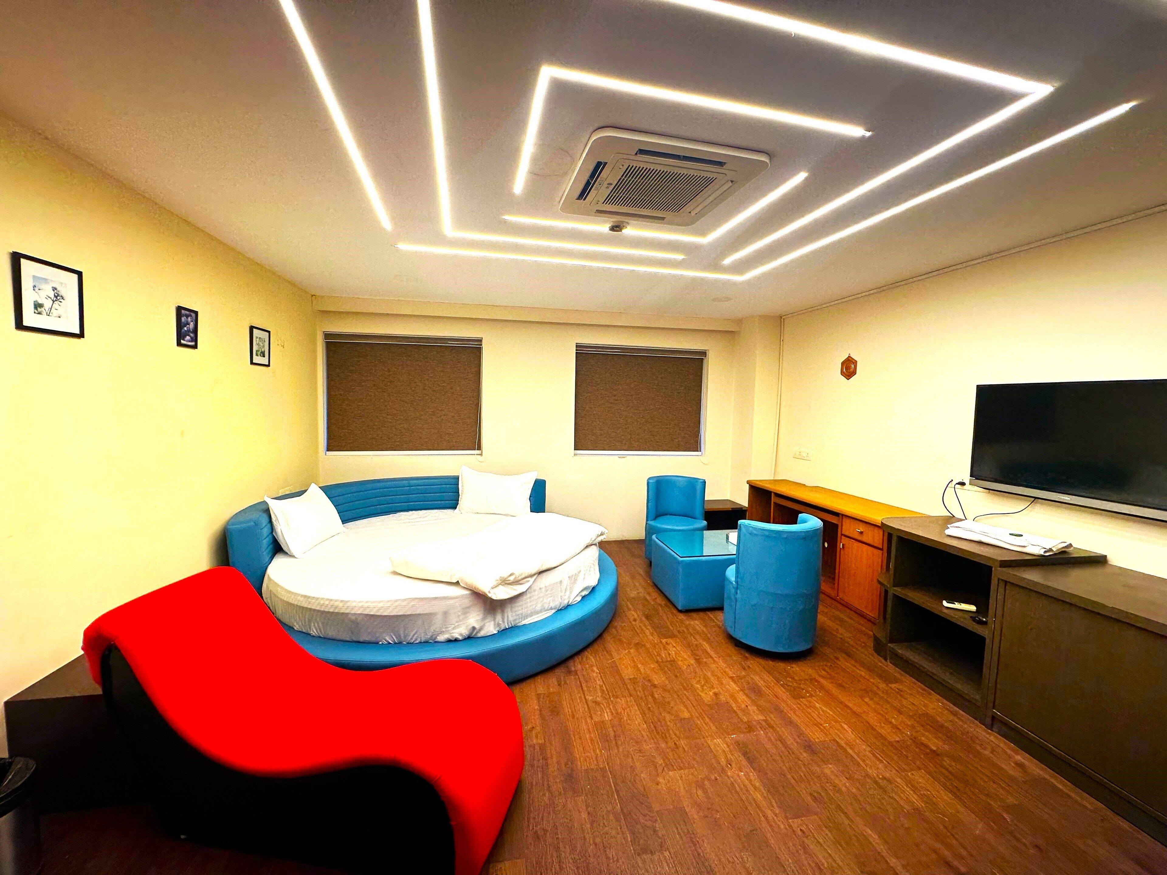 Una habitación de hotel moderna con una cama redonda, un televisor de pantalla plana y piso de madera.