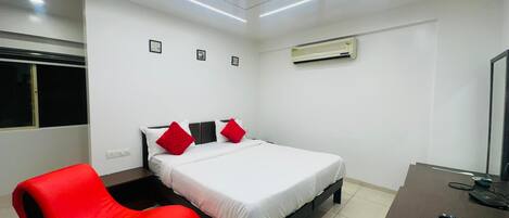 A modern bedroom with a bed, a red chair, a desk, and a ceiling light fixture.