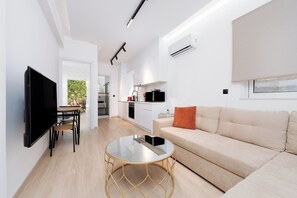 디럭스 아파트, 침실 1개, 파티오, 정원 전망 | 거실 공간 | 케이블 채널 시청이 가능한 50인치 TV