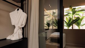 A modern bathroom with a glass shower enclosure, a white bathtub, and a large potted plant.